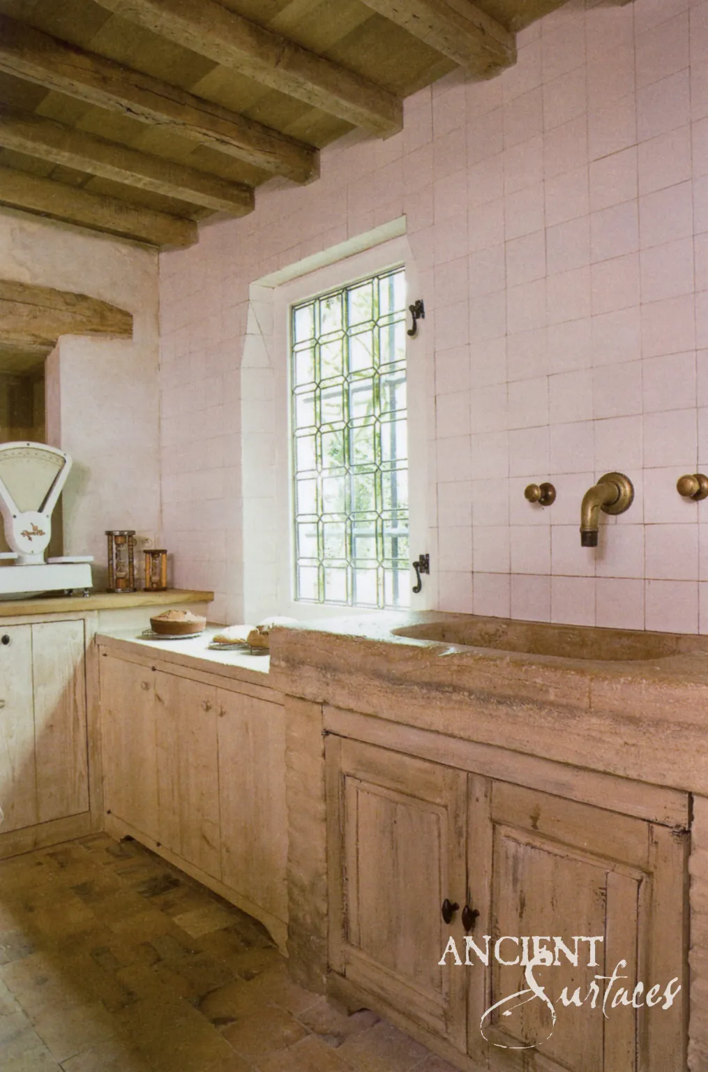Hand-carved antique limestone sink and reclaimed stone flooring in a rustic kitchen