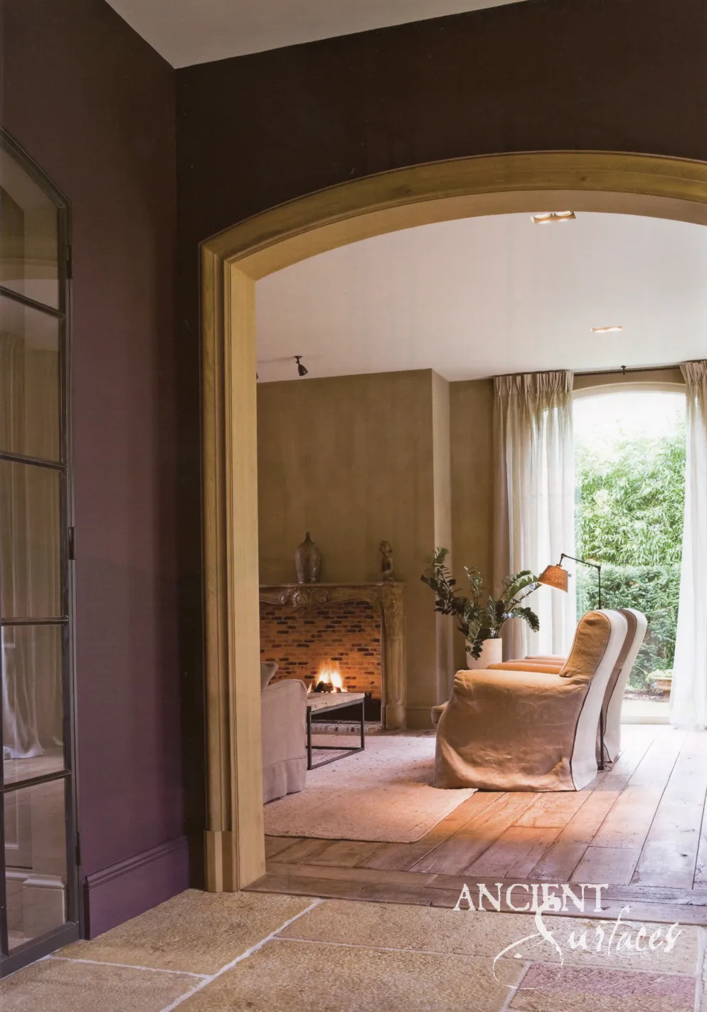 Reclaimed antique limestone flooring framing an arched stone fireplace room
