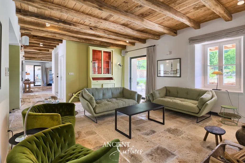 Villa living room with reclaimed limestone flagstone floors beneath an antique timber-beamed ceiling