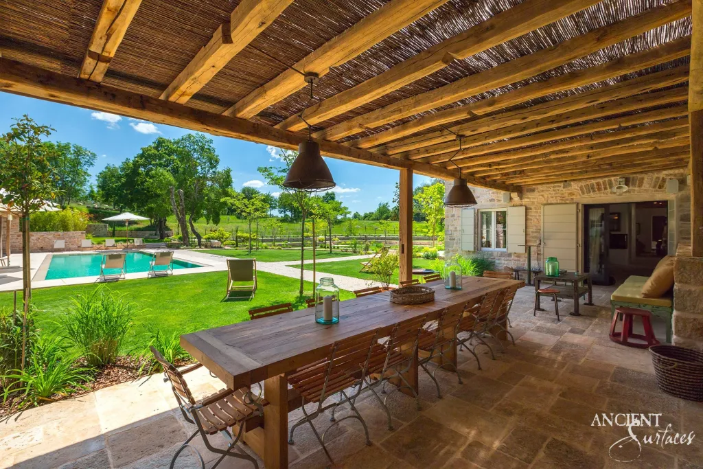 Reclaimed limestone terrace and pergola overlooking a villa pool and gardens
