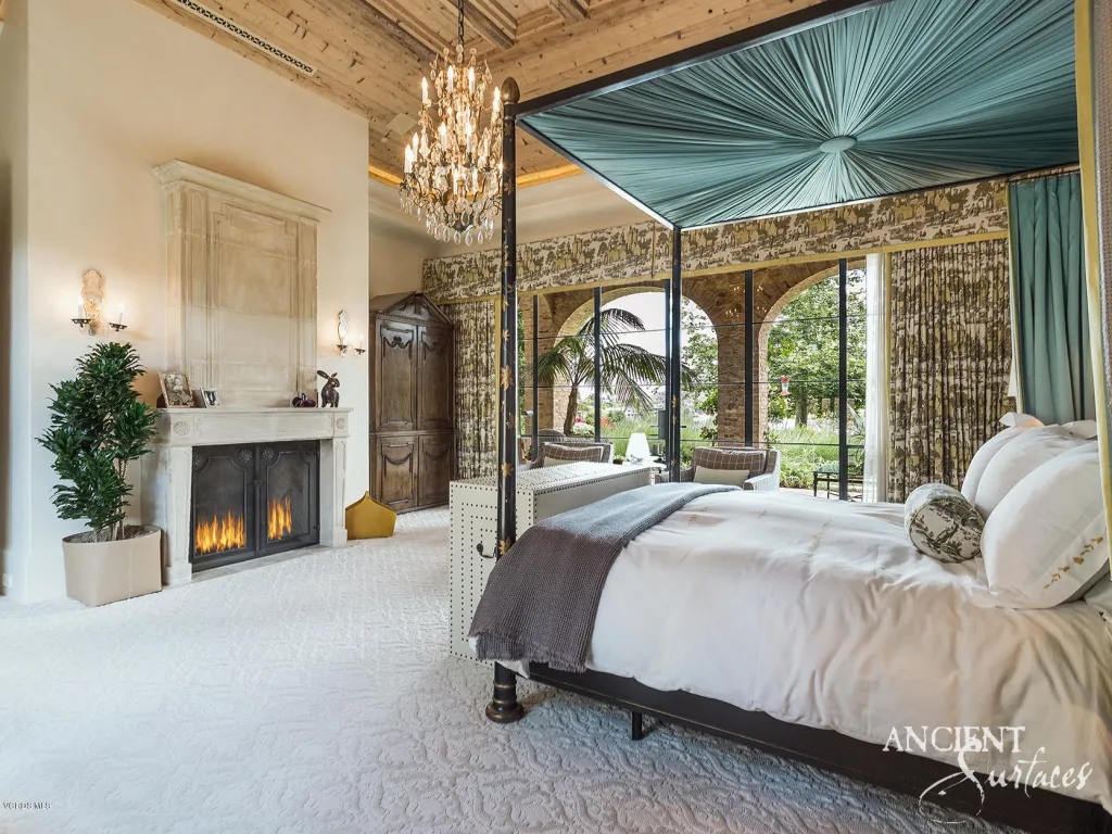 Reclaimed limestone fireplace and flooring in an elegant canopy-bed suite